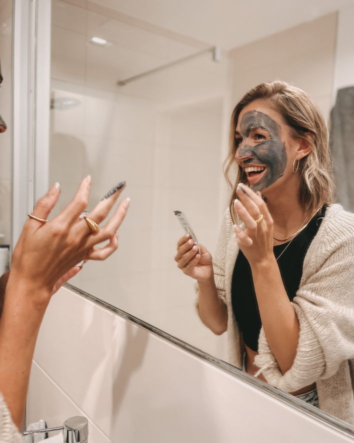 Laughing woman applies activated charcoal mask