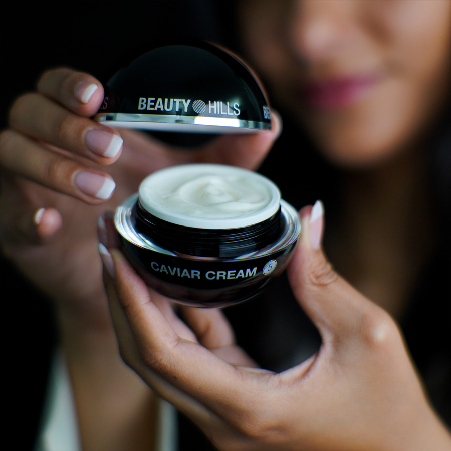 Femme ouvre la crème pour le visage Caviar Cream